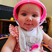 Maeve joined the competition — help win amazing prizes! baby, bib, bucket_hat, chair, checkered_dress, child, closeup, cute, drool, face, furniture, indoor, infant, pacifier, person, playful, plush_toy, smiling, table, toy