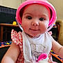 baby, bib, bucket_hat, chair, checkered_dress, child, closeup, cute, drool, face, furniture, indoor, infant, pacifier, person, playful, plush_toy, smiling, table, toy
