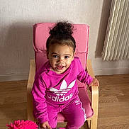 Kamélia participe au concours pour gagner de l'argent avec cette photo : toddler, child, pink_clothing, adidas, chair, indoor, wooden_floor, radiator, duster, smiling, curly_hair, socks, person, furniture, happy, casual, portrait, young_child, seated, playful