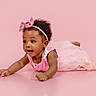 Malani joined the competition — help win amazing prizes! baby, child, girl, pink_dress, headband, sparkly_bow, curly_hair, tummy_pose, studio_photo, pink_background, smiling, cute, infant, portrait, happy, playful, young_child, closeup, adorable, fashion