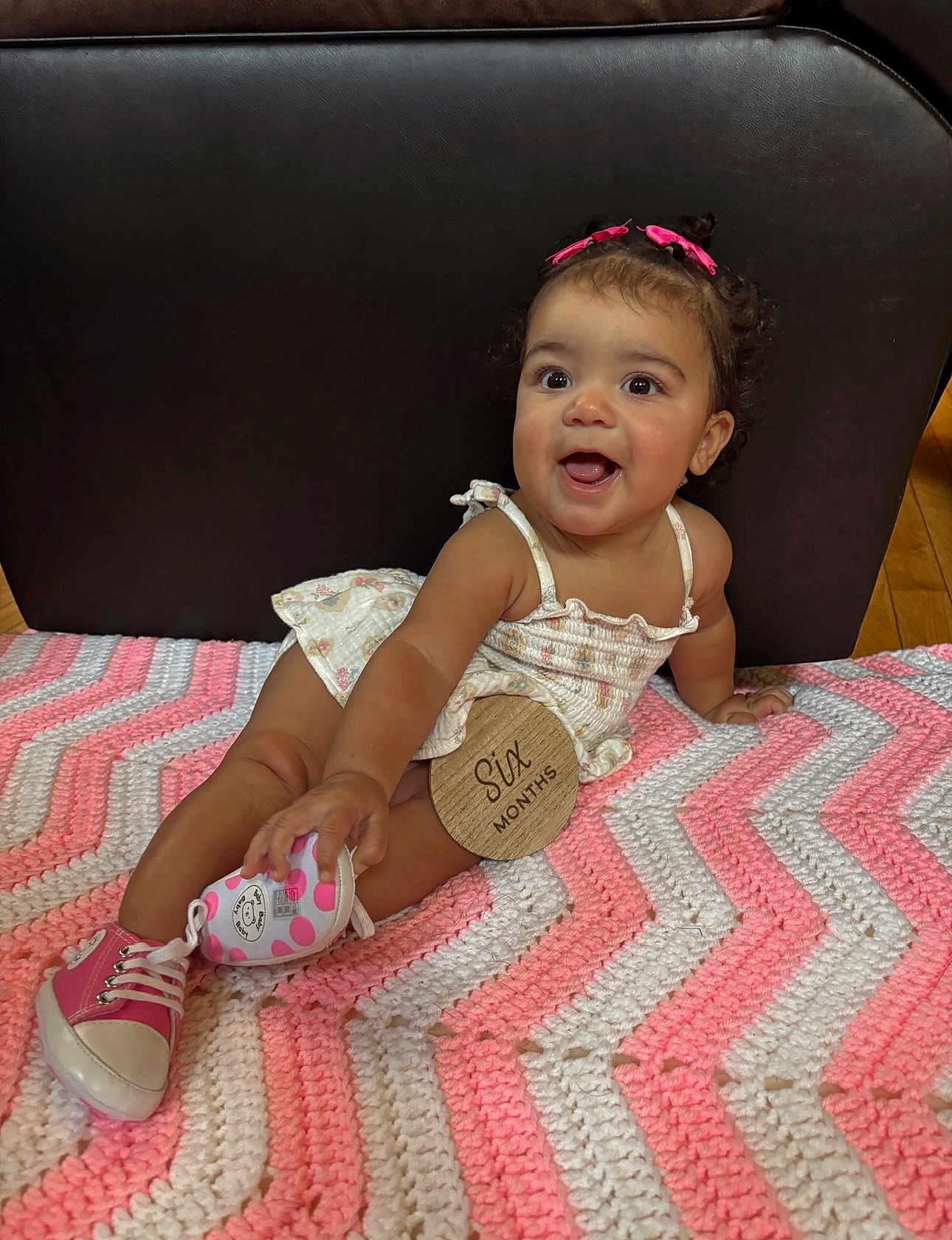 Tyla joined the competition — help win amazing prizes! baby, child, infant, smiling, happy, pink, hair_bows, shoe, polka_dots, blanket, crochet, pattern, sitting, cute, indoors, floor, wood, clothing, person, portrait