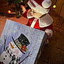 baby, carpet, child, christmas, christmas_tree, cozy, curious, decorations, festive, gift_box, holiday, holiday_lights, indoor, person, red_clothing, santa_hat, seasonal, snowman, toddler, white_fur_trim