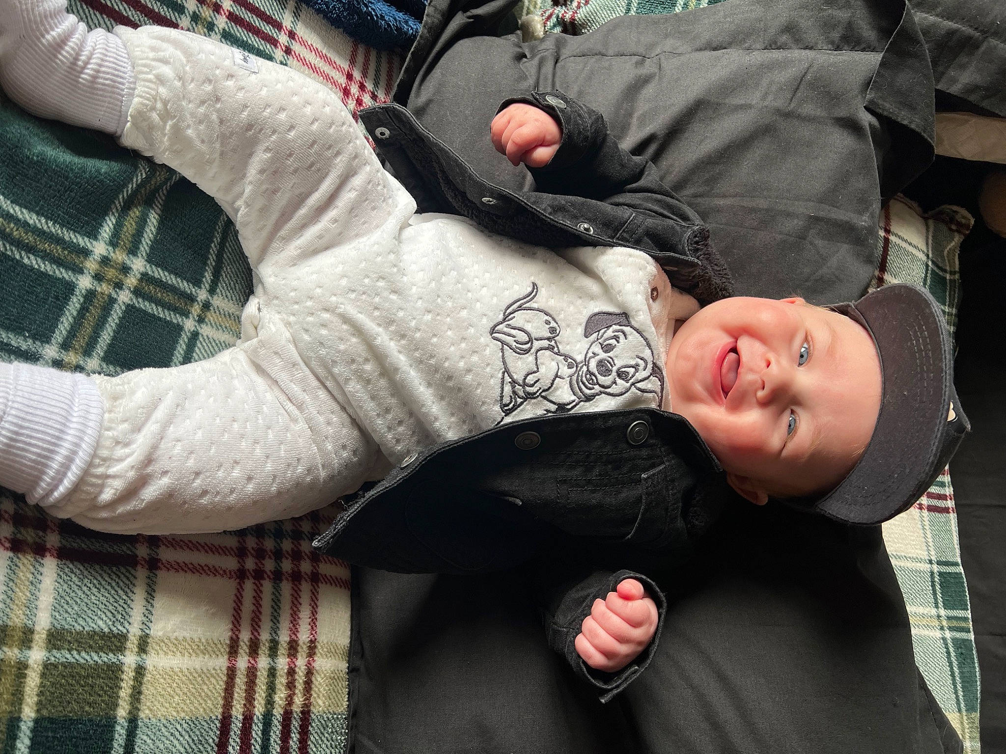 Jaxson is registered to the contest to win money with this photo: arm, black_hair, comfort, cool, elbow, finger, gesture, hairstyle, hand, happy, headwear, joint, pattern, person, plaid, sitting, sleeve, smile, t_shirt, tartan