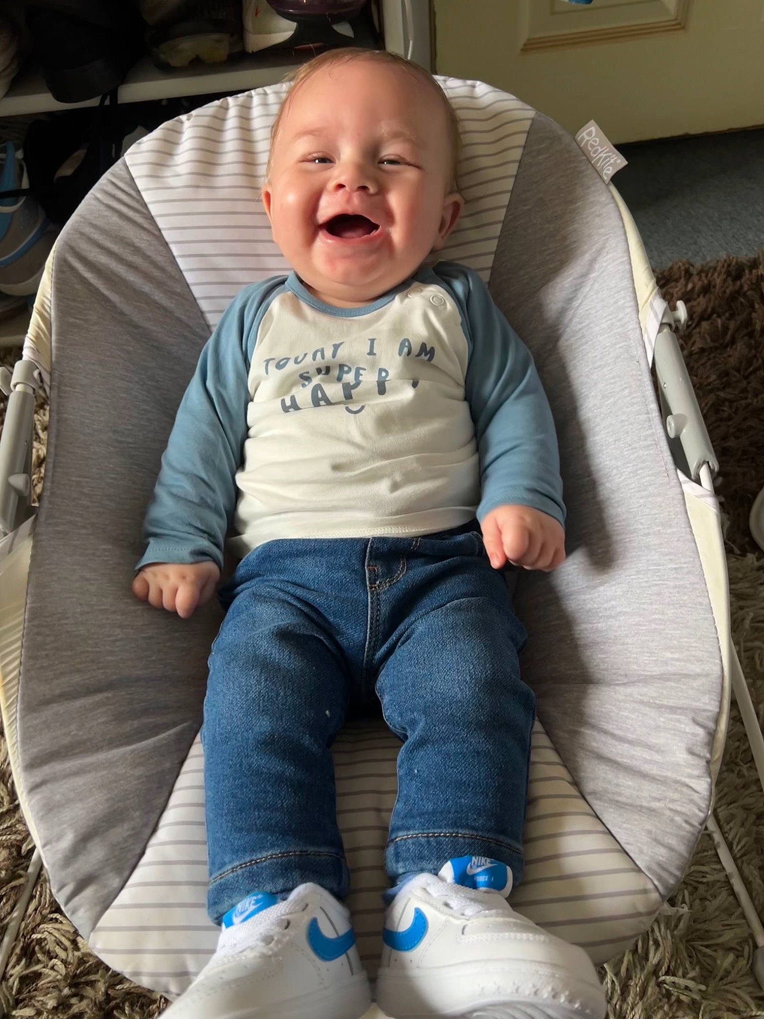 Jaxson is registered to the contest to win money with this photo: baby, baby_toddler_clothing, black, car_seat, chair, child, comfort, cool, electric_blue, face, fun, grass, lap, leg, mouth, person, sitting, smile, style, thigh