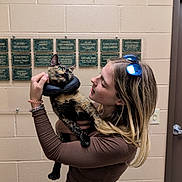 Rosie joined the competition — help win amazing prizes! woman, cat, indoor, tortoiseshell_cat, protective_collar, plaque, beige_wall, long_sleeve_shirt, sunglasses, blonde_hair, holding_pet, affection, pet, human, portrait, casual_clothing, bracelet, door, light_switch, expression