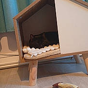 Fifille a rejoint le concours — aidez-le/la à gagner de superbes lots ! animal, black_cat, blanket, cat_house, comfortable, cozy, curtains, feline, floor, home_interior, indoor, modern_design, pet, quiet, resting, sleeping_cat, soft_lighting, toy_fish, wooden_furniture, wooden_legs