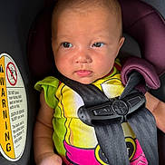 Ayannah joined the competition — help win amazing prizes! baby, child, car_seat, safety_harness, clothing, infant, seatbelt, portrait, person, cute, serious, indoors, seat, head, face, hand, expression, closeup, colorful, safety
