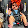 baby, child, car_seat, headband, red_bow, blue_outfit, straps, infant, foot, hand, face, expression, seatbelt, indoor, floor, footwear, person, cute, portrait, safety