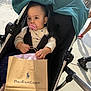 baby, black_stroller, casual, child, clothing, daytime, footwear, hand, infant, outdoor, pacifier, people, person, polo_ralph_lauren, retail, shopping_bag, sidewalk, stroller, sunlight, urban