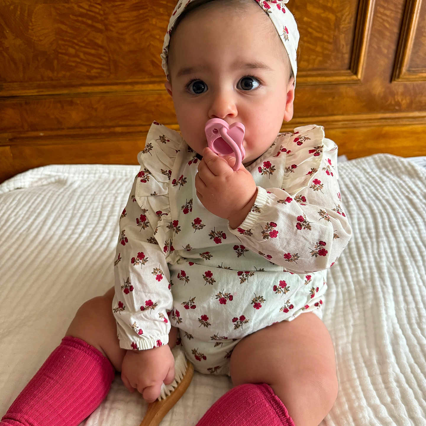 Mila Vardanyan joined the competition — help win amazing prizes! adorable, baby, bed, child, clothing, cute, floral_clothing, headband, indoors, infant, pacifier, person, pink, pink_socks, portrait, quilted_bedspread, sitting, wooden_brush, wooden_headboard, young_child