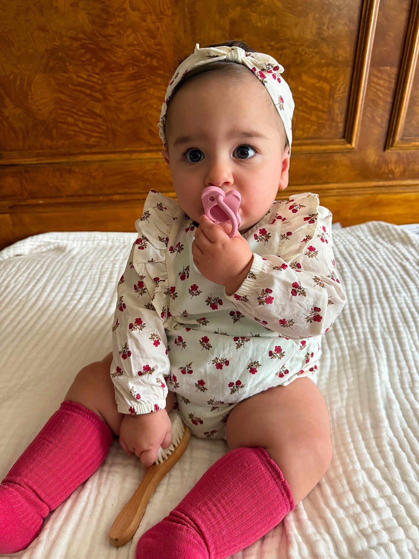 Mila Vardanyan joined the competition — help win amazing prizes! adorable, baby, bed, child, clothing, cute, floral_clothing, headband, indoors, infant, pacifier, person, pink, pink_socks, portrait, quilted_bedspread, sitting, wooden_brush, wooden_headboard, young_child
