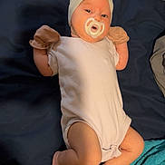 Nellie joined the competition — help win amazing prizes! baby, infant, pacifier, headband, bow, onesie, mittens, barefoot, lying_down, bed, blanket, blue_blanket, skin, cute, newborn, child, sleepy, resting, indoors, person