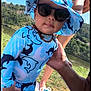 Ayaan participe au concours pour gagner de l'argent avec cette photo : toddler, child, sunglasses, hat, swimsuit, blue, shark_pattern, outdoor, lake, grass, sunny, adult_hand, necklace, person, nature, summer, water, sky, vacation, family