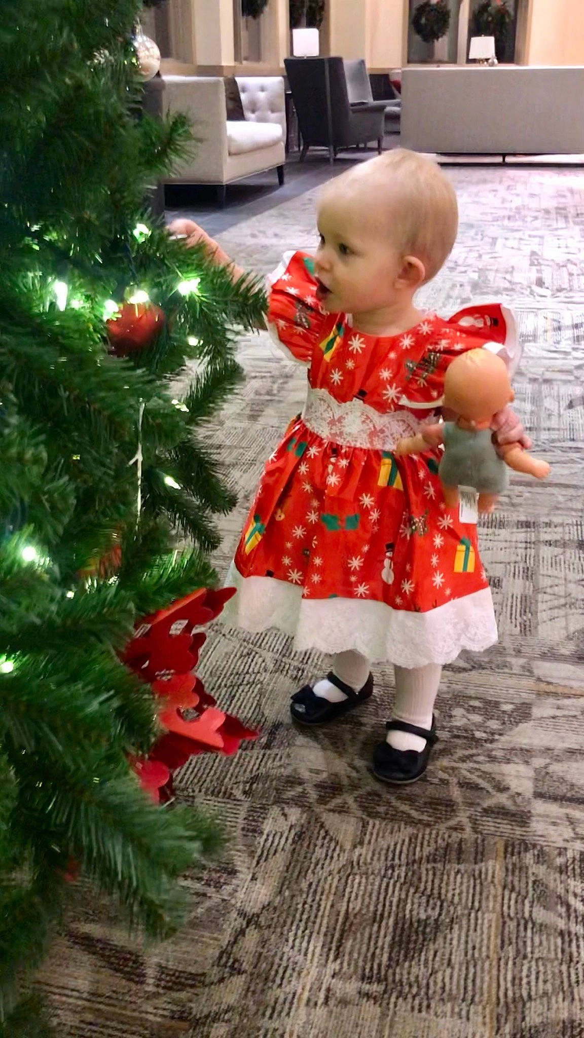 Layla is registered to the contest to win money with this photo: baby, baby_toddler_clothing, christmas_decoration, christmas_ornament, christmas_tree, conifer, dress, event, evergreen, flooring, grass, happy, holiday, holiday_ornament, ornament, pattern, person, plant, toddler, tree
