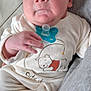 baby, infant, pacifier, onesie, clothing, face, hand, cute, sleeping_bear, fabric, texture, soft, portrait, newborn, skin, expression, comfort, indoor, person, closeup