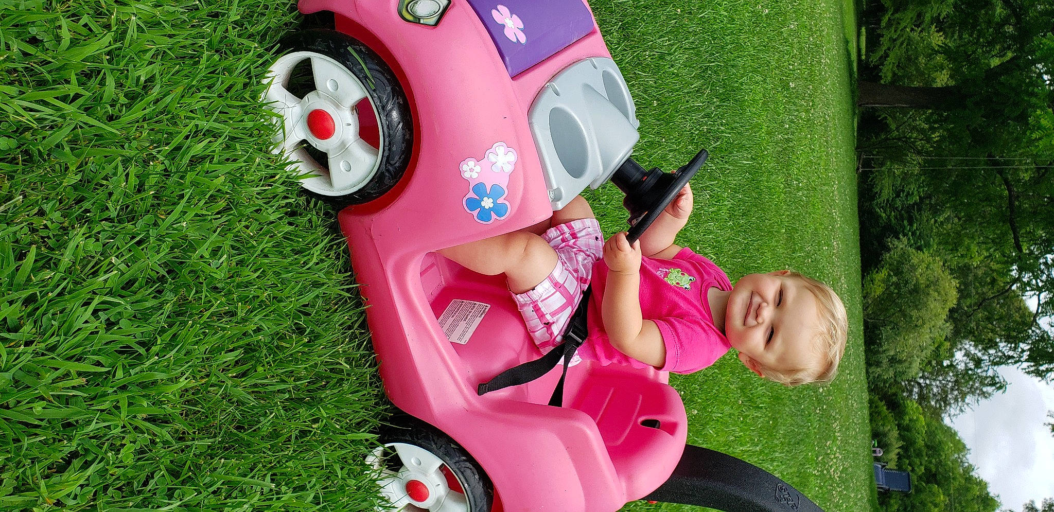 Annie joined the competition — help win amazing prizes! automotive_exterior, baby_toddler_clothing, fun, grass, green, happy, joy, leisure, magenta, motor_vehicle, person, pink, plant, recreation, red, riding_toy, smile, tire, toddler, toy