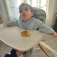 Rayan participe au concours pour gagner de l'argent avec cette photo : toddler, child, high_chair, bread, food, indoor, sunlight, curious, expression, clothing, socks, floor, window, curtains, tray, seat, person, baby, legs, home