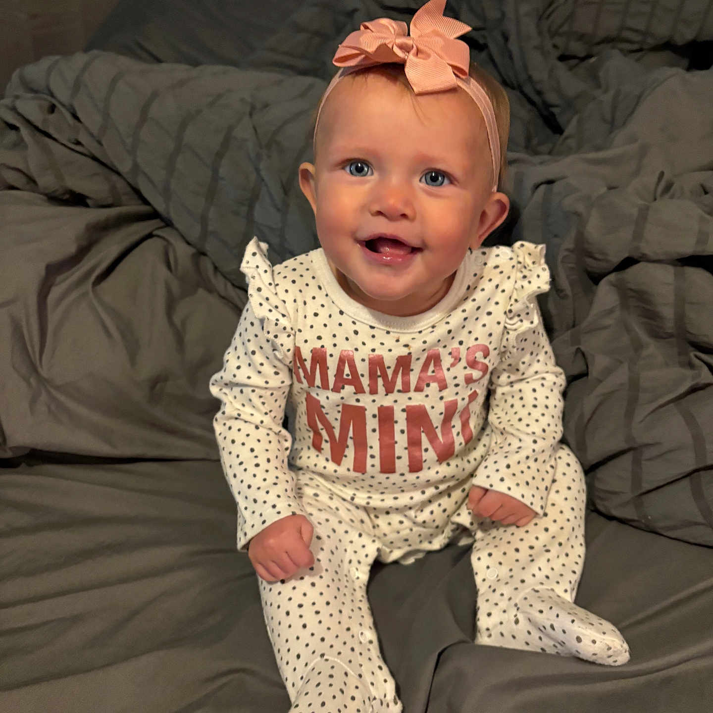 Ensley is registered to the contest to win money with this photo: baby, bed, blanket, blue_eyes, bow, child, clothing, cute, face, gray, happy, headband, indoors, infant, onesie, pink, polka_dot, portrait, sitting, smiling