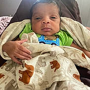Za'Kai is registered to the contest to win money with this photo: baby, child, blanket, elephant_pattern, green_shirt, hand, face, portrait, indoors, cozy, sleepy, newborn, soft_light, swaddled, cute, infant, resting, clothing, human, window_light