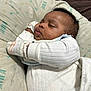 Za'Kai is registered to the contest to win money with this photo: baby, sleeping, infant, mittens, white_clothing, cushion, patterned_cushion, arrows, text_on_cushion, peaceful, indoors, blanket, closeup, soft_texture, resting, child, cute, cozy, portrait, newborn