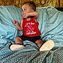 casual_clothing, child, comfort, couch, footwear, furniture, home_interior, indoor, looking_away, patterned_fabric, person, playful, portrait, red_tank_top, relaxed, sitting, small_shoes, stone_wall, toddler, young_child