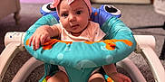 Reagan is registered to the contest to win money with this photo: baby, infant, child, headband, pink, bow, baby_seat, colorful, carpet, indoor, furniture, curious, reaching_hand, legs, feet, face, expression, room, door, soft_lighting