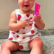 Nora joined the competition — help win amazing prizes! baby, child, smiling, headband, blue_headband, strawberry_pattern, white_outfit, sitting, marble_surface, happy, holding_object, pink_object, cute, infant, indoors, portrait, legs, barefoot, skin, face
