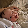 baby, smiling, infant, clothing, hand, face, lying_down, happy, cute, child, person, bed, fabric, soft, morning, skin, portrait, comfort, indoors, closeup