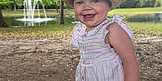 Gwendalyn joined the competition — help win amazing prizes! baby, child, smiling, hat, romper, outdoor, park, fountain, grass, tree, sunny, nature, happy, playful, person, summer, daylight, cute, portrait, standing