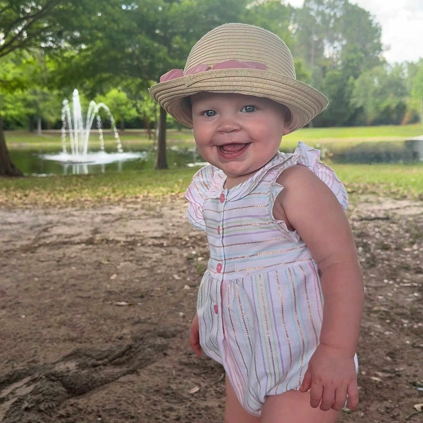 Gwendalyn joined the competition — help win amazing prizes! baby, child, cute, daylight, fountain, grass, happy, hat, nature, outdoor, park, person, playful, portrait, romper, smiling, standing, summer, sunny, tree