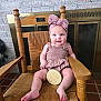 baby, child, infant, pink_bow, headband, wooden_chair, smiling, blue_eyes, four_months_sign, cozy, indoor, brick_wall, fireplace, cute, sitting, plush, wood, floor_tiles, happy, portrait