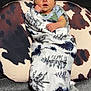 newborn, baby, blanket, sleeping, infant, pillow, cow_print, pattern, wrapped, resting, soft, cozy, indoor, bedroom, cute, peaceful, child, person, nursery, comfort