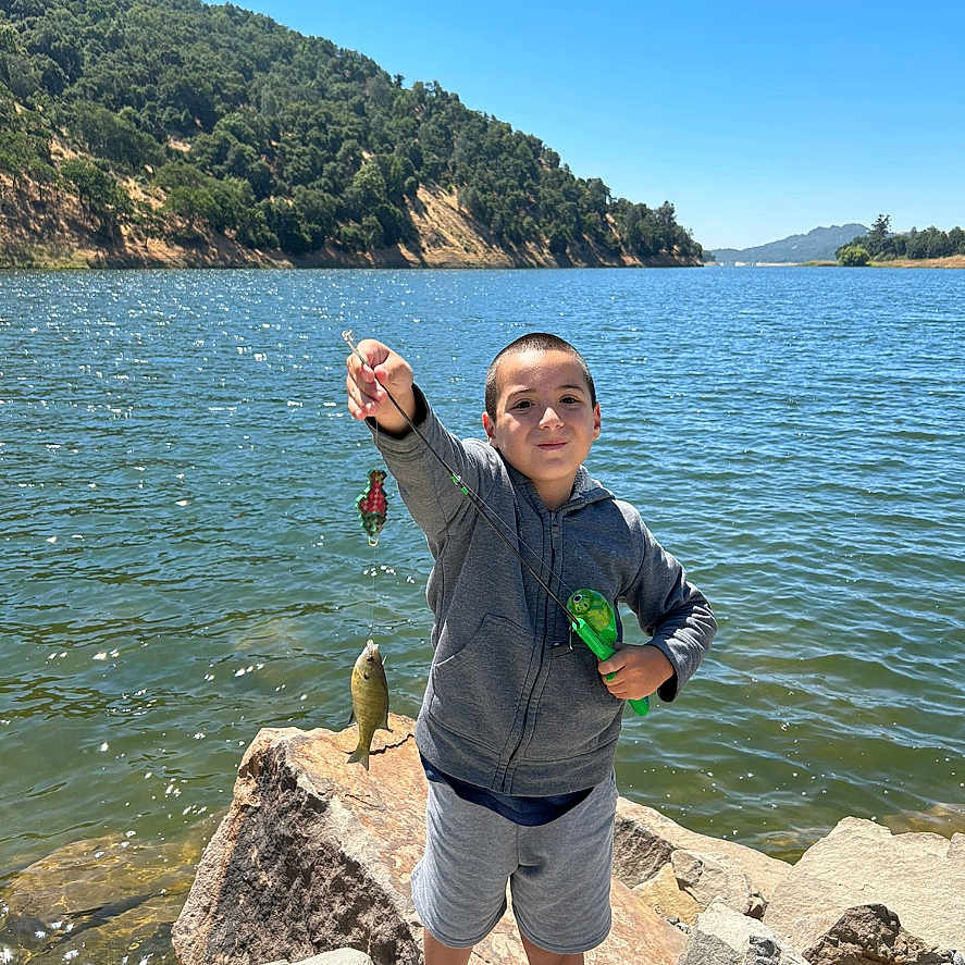 Joshua is registered to the contest to win money with this photo: bodypart, boy, child, clothing, face, finger, fishing, footwear, hand, head, leisureactivities, male, outdoors, person, photography, portrait, rock, shoe, shorts, water