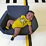 Dante is registered to the contest to win money with this photo: baby, child, armchair, yellow_clothing, black_socks, floor, striped_floor, indoor, modern_furniture, relaxed, cute, infant, person, small_person, comfortable, seated, portrait, fashion, cozy, bright_colors