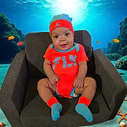 Dante is registered to the contest to win money with this photo: baby, child, armchair, orange_clothing, blue_clothing, hat, socks, smiling, indoor, underwater_background, fish, coral, sea_life, digital_background, cute, portrait, happy, infant, seated, playful