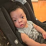 Dante joined the competition — help win amazing prizes! baby, child, car_seat, black, gray_shirt, patterned_clothing, curly_hair, wide_eyes, indoor, floor, infant, person, cute, seatbelt, looking_at_camera, skin, arm, young_child, casual, expression
