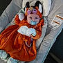 Lilith is registered to the contest to win money with this photo: baby, pacifier, costume, fox, headband, flowers, cushion, clothing, infant, cute, lying_down, indoors, baby_seat, soft_toys, orange, white, gloves, footwear, person, portrait