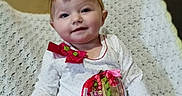 Willow is registered to the contest to win money with this photo: baby, child, smiling, bow, yellow_bow, christmas_tree, holiday, knitted_blanket, indoor, cute, portrait, sitting, clothing, patterned_pants, decorative_patch, festive, soft_lighting, happy, young_child, home