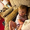 Willow is registered to the contest to win money with this photo: blanket, carpet, child, clothing, couch, cozy, curtains, diaper, face, foot, furniture, home, indoor, lamp, person, pillow, seated, smiling, toddler, wooden_wall