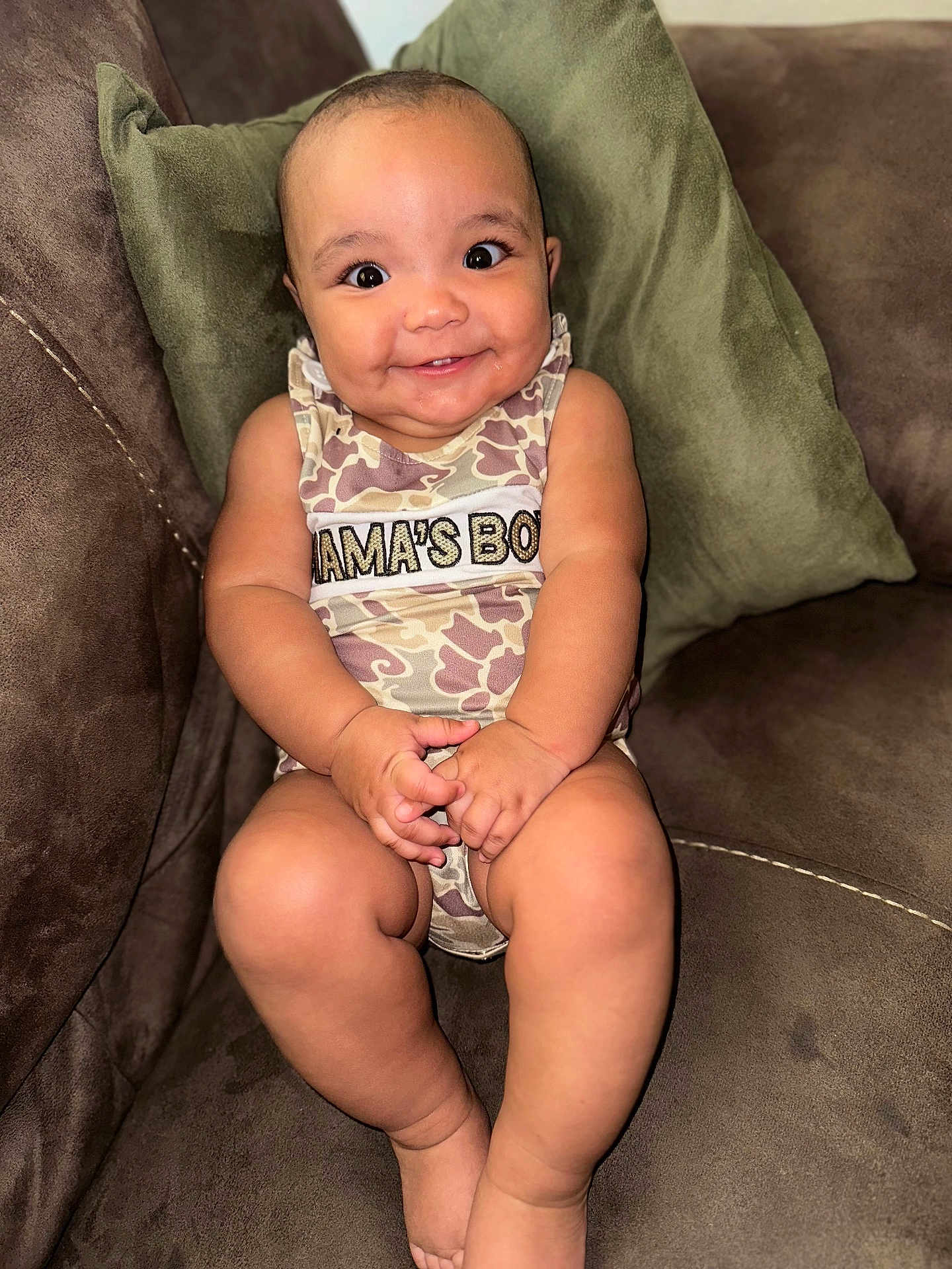 Eziah is registered to the contest to win money with this photo: baby, child, smiling, sitting, couch, pillow, clothing, indoor, face, person, happy, cute, infant, camouflage, skin, hands, legs, eyes, mouth, expression