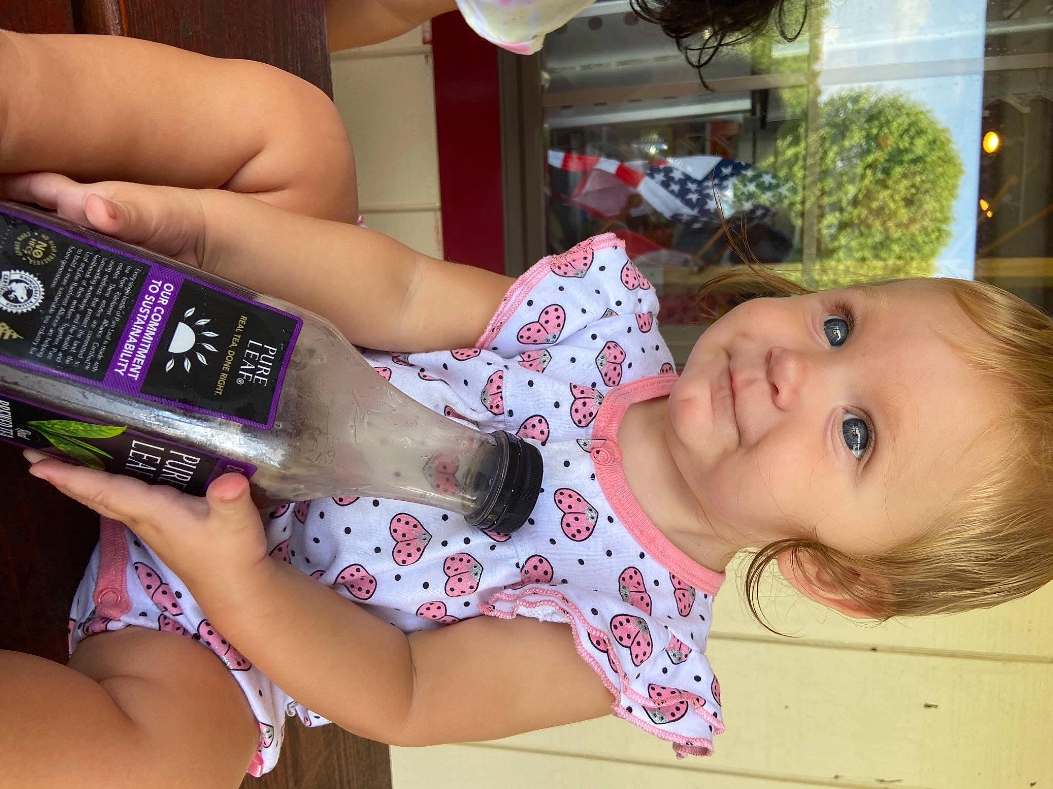 Kaelynn is registered to the contest to win money with this photo: alcoholic_beverage, baby_toddler_clothing, drink, drinkware, eyelash, finger, food, fun, hand, happy, human_body, mouth, nail, person, plastic_bottle, skin, smile, thigh, thumb, toddler