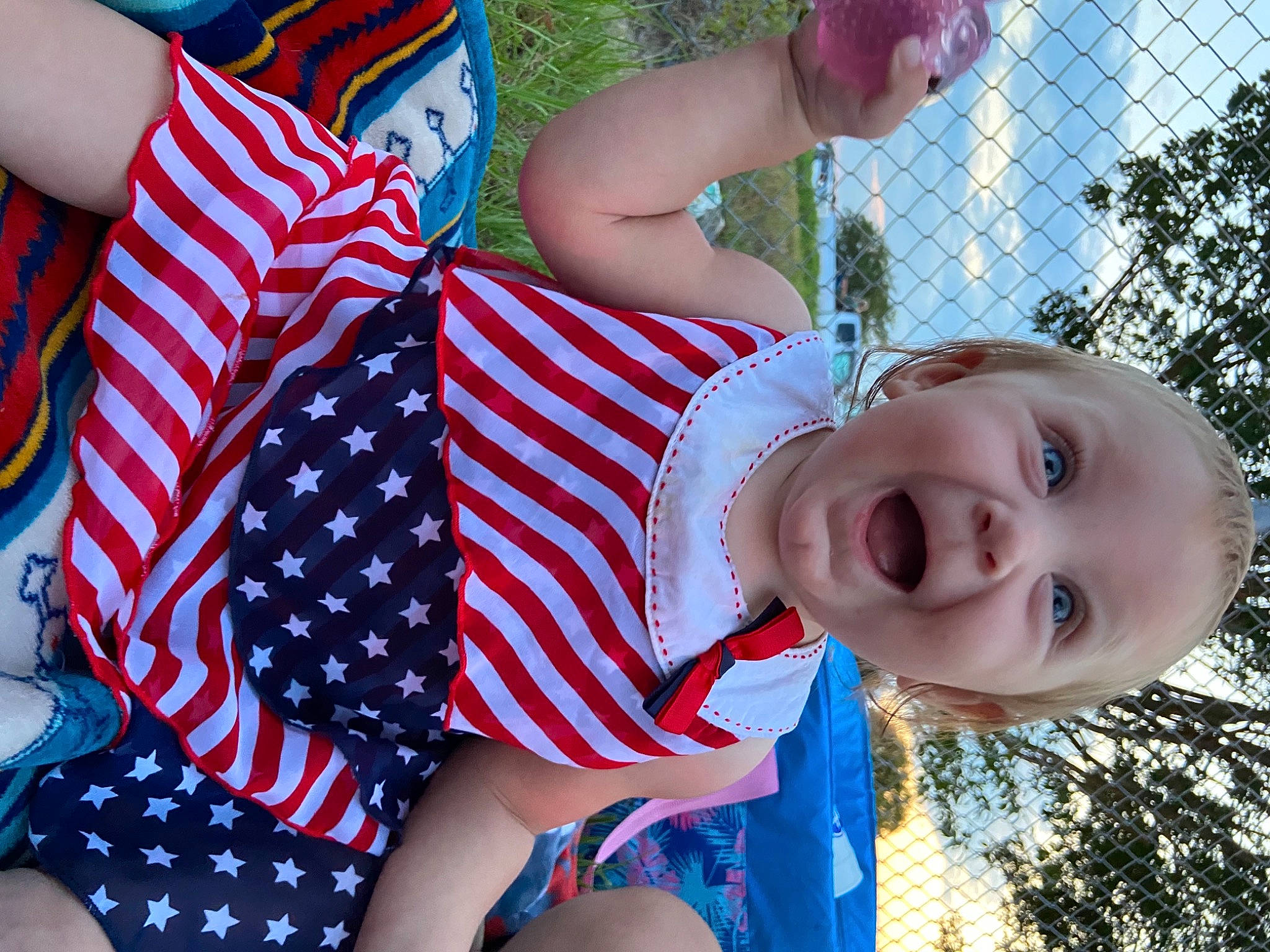 Kaelynn is registered to the contest to win money with this photo: baby_toddler_clothing, child, event, fence, flag_of_the_united_states, fun, grass, happy, leisure, pattern, people_in_nature, person, plant, recreation, red, smile, summer, sunglasses, toddler, tree