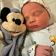 Hudson is registered to the contest to win money with this photo: baby, newborn, sleeping, plush_toy, mickey_mouse, soft_toys, hat, clothing, hand, bed, blanket, infant, cute, peaceful, portrait, child, toy, closeup, indoors, rest