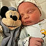 baby, newborn, sleeping, plush_toy, mickey_mouse, soft_toys, hat, clothing, hand, bed, blanket, infant, cute, peaceful, portrait, child, toy, closeup, indoors, rest