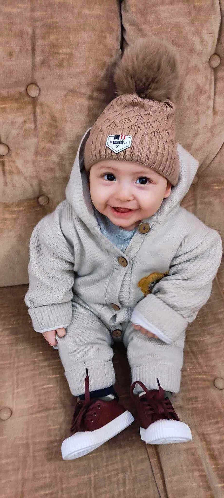 Amine participe au concours pour gagner de l'argent avec cette photo : baby, child, smiling, hat, pom_pom, knitwear, sitting, couch, buttoned_sweater, shoes, cozy, indoors, cute, happy, portrait, person, face, warm_clothing, infant, button