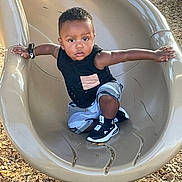 Justin joined the competition — help win amazing prizes! toddler, child, slide, playground, outdoor, wood_chips, black_shoes, black_shirt, shorts, arms_outstretched, determined_expression, daylight, play, fun, park, casual_clothing, active, young_child, person, recreation