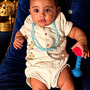 Aarav is registered to the contest to win money with this photo: baby, blue_necklace, child, comfortable, cream_outfit, curious_eyes, cute, decorative, expression, furniture, golden_decor, indoor, infant, luxury, playful, portrait, sitting, toy, velvet_chair, young_child