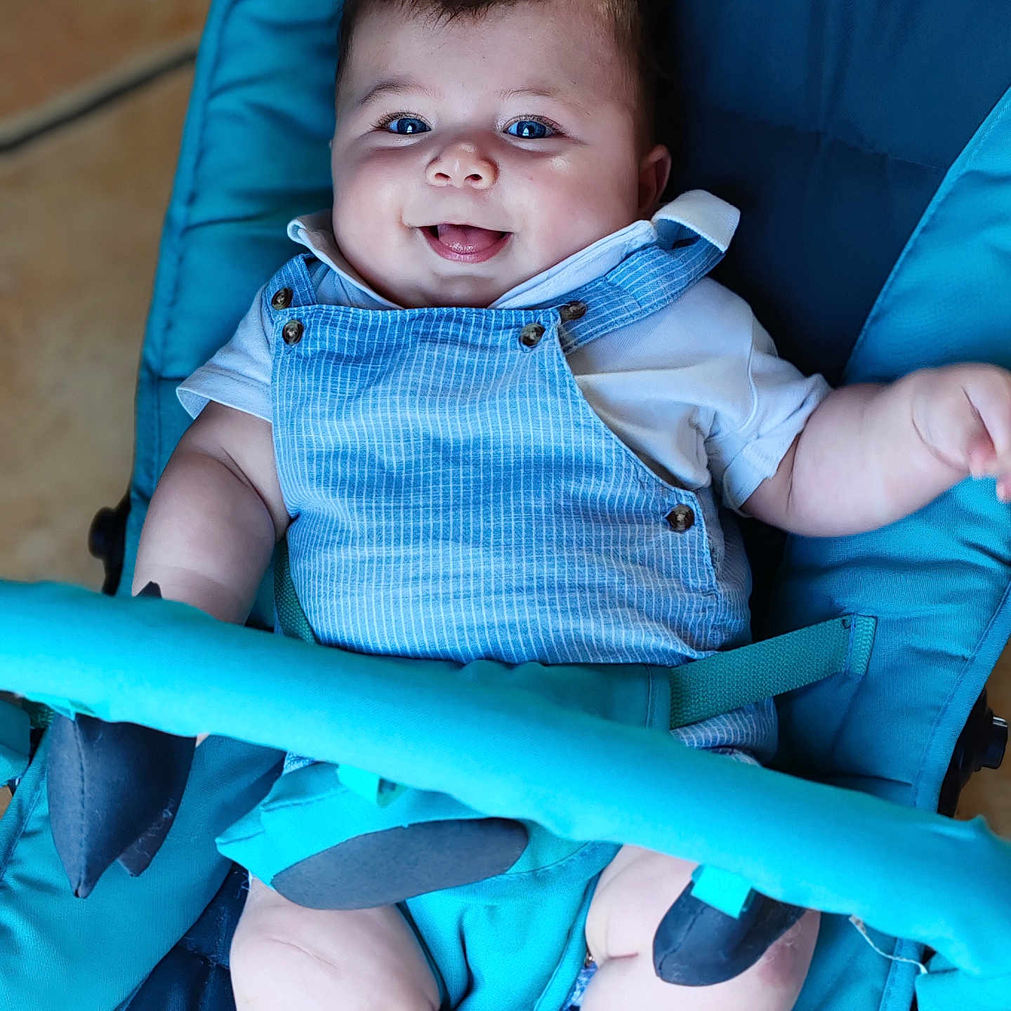 Sacha participe au concours pour gagner de l'argent avec cette photo : baby, baby_accessory, baby_seat, baby_toys, blue, blue_overall, child, chubby_cheeks, clothing, cute, happy, indoor, infant, person, playful, portrait, seatbelt, smiling, soft_toys, tongue_out