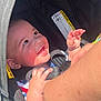 arm, baby, car_seat, child, closeup, clothing, cute, face, hand, happy, indoor, infant, interaction, person, protective, safety, seatbelt, smiling, sunlight, young