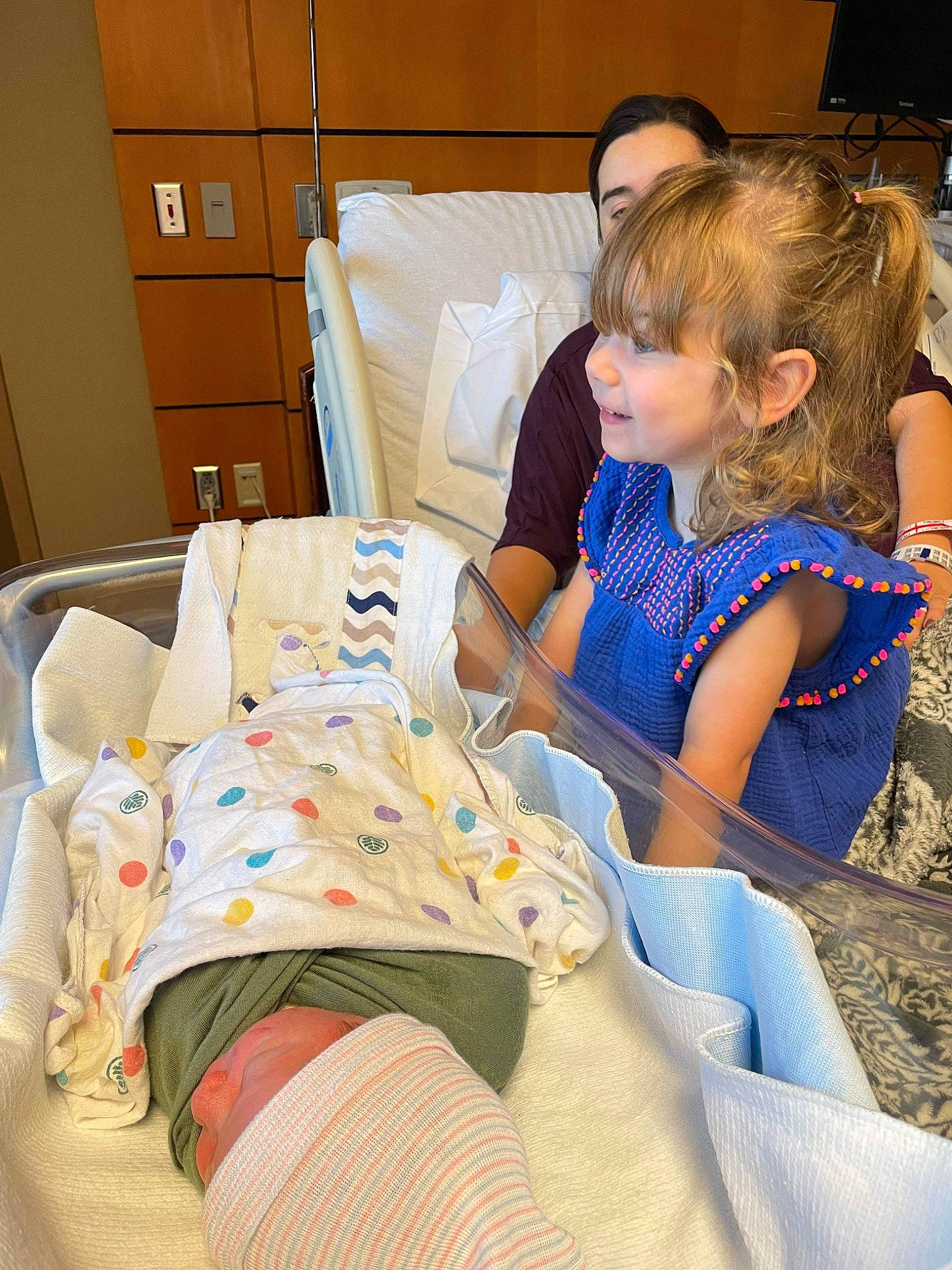 Lucy is registered to the contest to win money with this photo: baby, cabinetry, chest_of_drawers, child, comfort, drawer, event, hospital, hospital_bed, human_leg, knee, lap, leisure, linens, patient, person, pillow, sitting, t_shirt, thigh